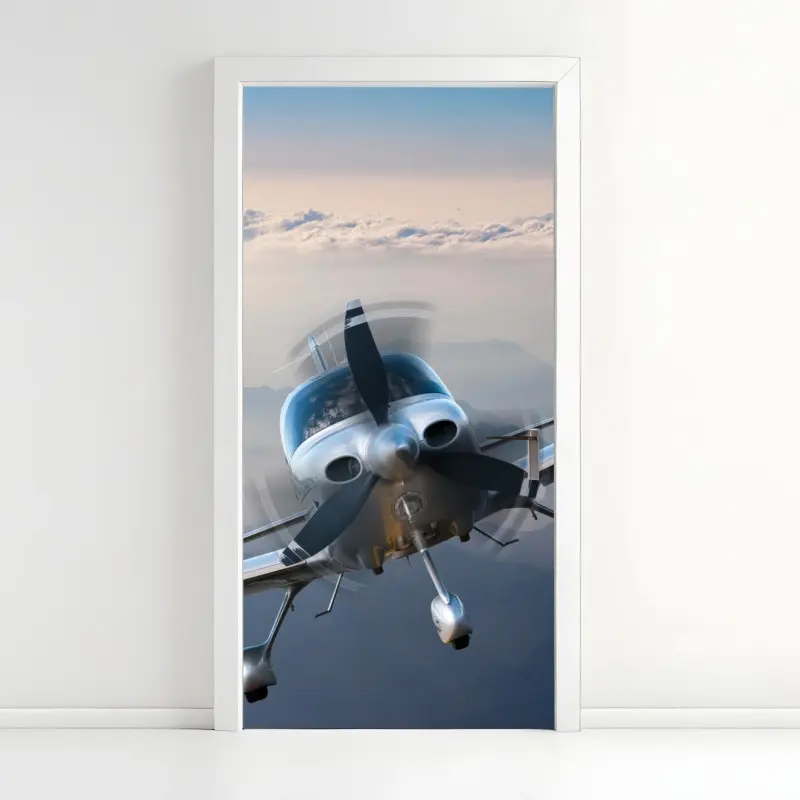 Türaufkleber silbernes propellerflugzeug über nebeligen bergen